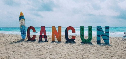 Picture of a Cancun sign in Cancun, Mexico. The picture shows white letters on the beach spelling out Cancun.