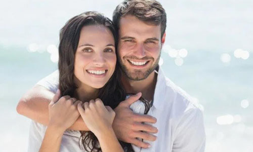 Picture of a man,  happy with his hair transplant  procedure he had in Cancun, Mexico.  The man is shown with his arm around a woman and both are smiling at the camera..