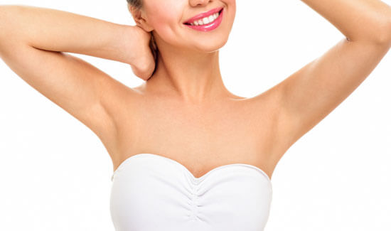 Picture of a woman holding her arms up and happy with her perfect arms liposuction procedure she had with Cancun MedVentures in beautiful Cancun, Mexico.  The woman is wearing a white top and smiling to the camera.